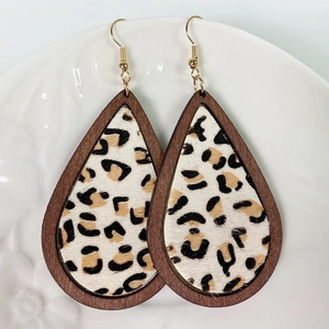 Detail shot of teardrop leopard print calf hair earrings with wooden borders on a tray