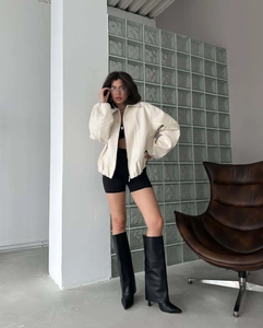 Detail of a zip-up baseball jacket with a stand collar and drop shoulders in cream white