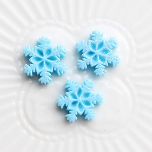 Close-up of blue glitter snowflake resin charms for DIY craft hats and hair accessories