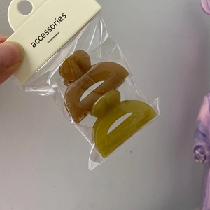 Detail of two mini jelly hair clips in brown and lime green with clear packaging