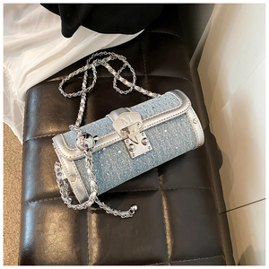 Detail of blue denim cylinder bag with rhinestones and silver chain strap details