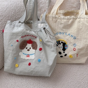 Close-up of cute puppy embroidery and drawstring on canvas tote bags in grey and cream
