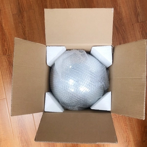 Detail view of a reflective disco mirror ball secured with foam corners in a cardboard box