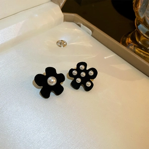 Detailed macro shot of black velvet flower earrings with pearl accents in a jewelry box