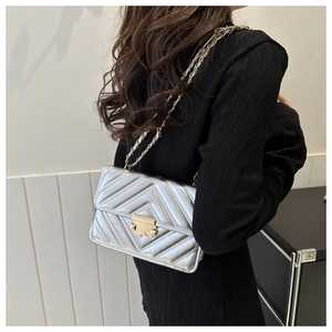 Sac à chaîne matelassé argenté avec texture en V et fermoir métallique sur un mannequin