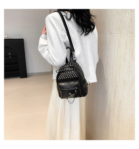 Detail of a black punk PU mini backpack featuring silver studs and a metallic cross charm