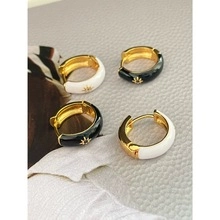 Detailed macro view of black and white enamel earrings with golden star relief accents