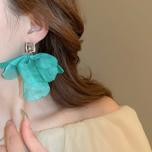 Detail view of a model wearing a green tulle flower earring with crystal stud