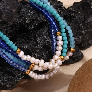 Macro shot of freshwater pearls and blue crystal beads on a textured dark rock