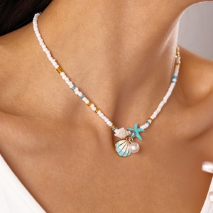 Detail of beach style necklace with blue shell and starfish charms on a female model