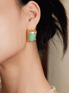 Close-up of vintage 18K gold frame earring with green rectangle gemstone on model