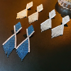 Detailansicht geometrischer Quastenohrringe in Gold, Silber und Blau mit funkelnden Kristallen