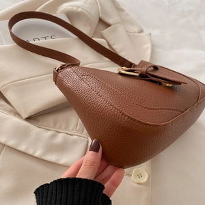 Close-up of the curved bottom and litchi texture on a brown shoulder bag
