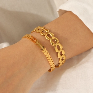Stacked 18k gold plated stainless steel wheat and link chain bracelets on model's wrist