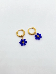 Macro detail of gold-plated stainless steel hoop earrings with blue floral charms