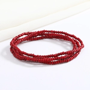 Detailed close-up of vibrant red multi-layer beaded waist chain on a white fabric background