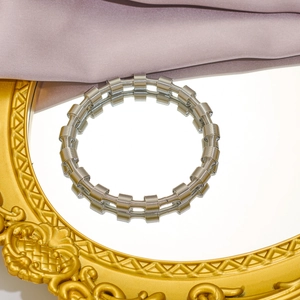 Elegant silver stainless steel spring spiral bracelet displayed on a vintage mirror