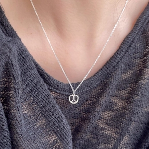 Close-up of 925 sterling silver pretzel knot necklace on model neck with lace background