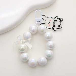 Macro shot of pearl beaded keyring with a cow pattern bunny and transparent bow charm