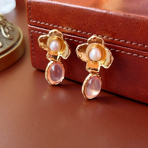 Macro shot of vintage gold earrings with white pearls and pink gemstone pendants