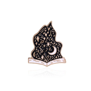 Macro detail of enamel pin showing stars and moon design on an open book motif