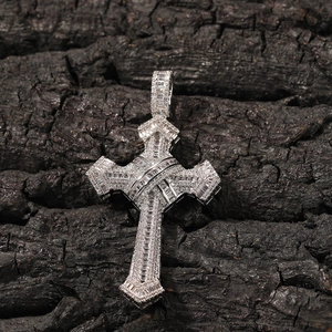 Macro shot of a silver hip hop cross pendant with inlaid cubic zirconia on dark wood