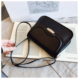 Détail du sac selle en cuir noir avec fermoir rotatif doré et surpiqûres de qualité