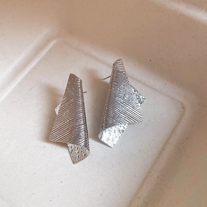 Close-up of silver irregular geometric metal studs with brushed texture and hammered finish