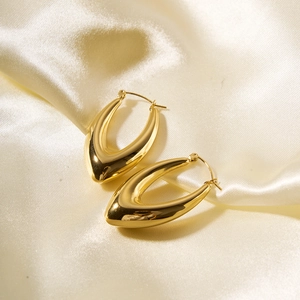 Detailed view of polished gold U-shaped hoop earrings on elegant silk fabric background