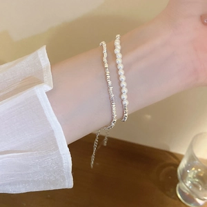 Double-layered silver nugget and pearl bracelet with adjustable chain on a woman's wrist