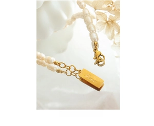 Macro shot of 18K gold plated Love tag and freshwater pearl bracelet with lobster clasp