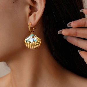 Macro shot of gold shell earring with rainbow abalone inlay on a model ear