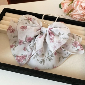 Dettaglio di un fermaglio per capelli a fiocco in chiffon floreale su vassoio in velluto