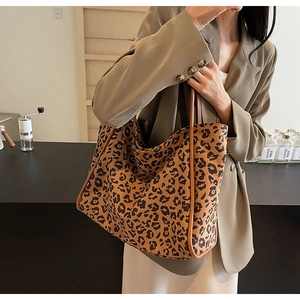 Detail of a large leopard print tote bag with brown handles on a khaki blazer model