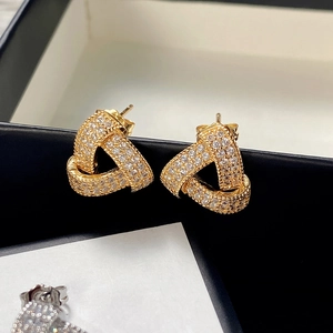 Close-up of interlocking gold triangle stud earrings with sparkling pavé cubic zirconia