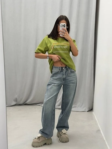 Selfie allo specchio con T-shirt verde stampata e jeans azzurri a gamba larga