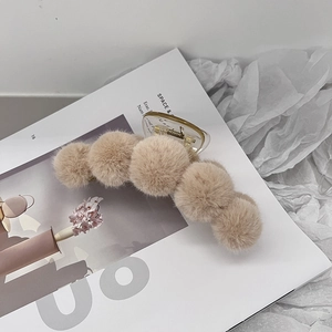 Close-up of beige faux fur plush hair claw clip on an open magazine background