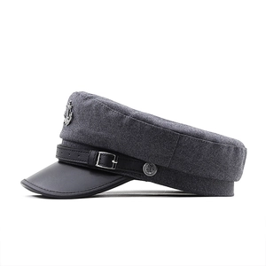 Détail de casquette en laine grise avec visière en cuir noir et badge ancre métallique