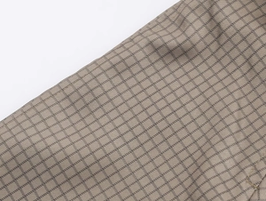 Close-up of khaki and dark grey plaid fabric texture with detailed weave pattern on coat