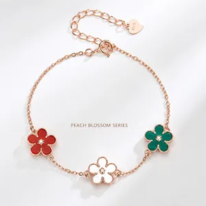 Macro detail of S925 rose gold bracelet with red, white, and green flower pendants