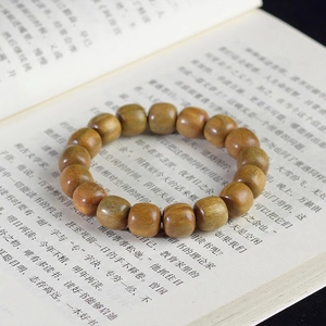 Detailed view of green sandalwood prayer beads with natural wood grain on a book