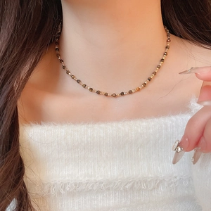 Close-up of faceted brown tiger eye beads and gold spacers on a model's neck