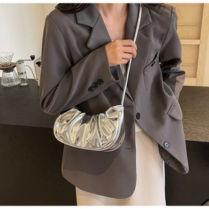 Detail of silver metallic pleated cloud bag with shiny mirror texture and crescent shape