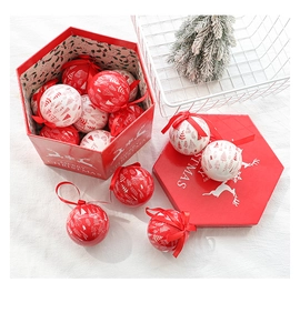 Red and white Christmas ball ornaments with tree patterns in a festive hexagon gift box