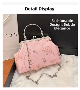 Close-up of pink satin clutch with floral embroidery, silver metal clasp, and beaded handle