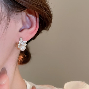 Close-up of a silver butterfly earring with shimmering pearls and zircon inlay on ear