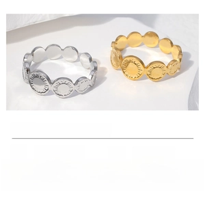 Detailed view of stainless steel open rings with engraved sunray patterns in gold and steel