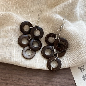 Close-up of bohemian coconut shell round hoop earrings with natural wood grain texture