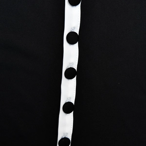 Detailed close-up of the black dress featuring a white button placket with round black buttons