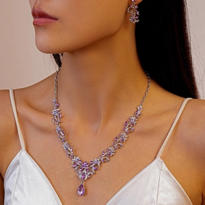 Detail of luxury rhinestone necklace set with purple teardrop crystals on a model